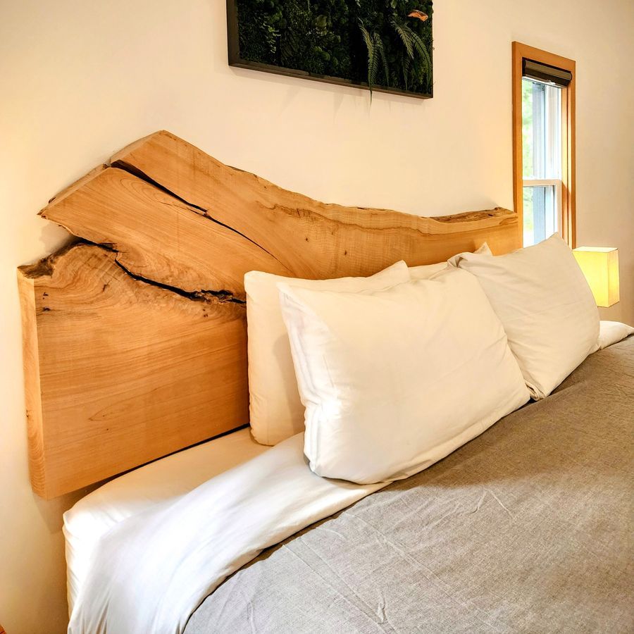 Bedroom in a converted garage suite in Ucluelet, with a live-edge wood headboard.